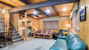 A log cabin interior with a staircase, a sofa, a leather couch, and a dining area. - Island Park Cabin Getaway < 24 Mi to Yellowstone! (Island Park)
