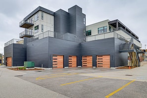 A modern building with multiple floors, large garage doors, and a staircase leading to an upper level. - Downtown Grand Haven Condo - Walk to Boardwalk! (Grand Haven)