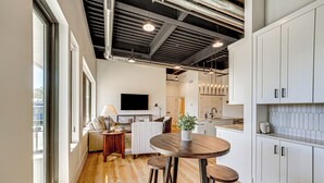 Una cocina moderna con armarios blancos, una mesa de comedor de madera y un ventanal grande.