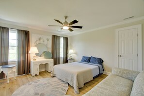 A bedroom with a bed, bedside tables, a desk, a chair, a ceiling fan, and a window with curtains. - Spacious Rural Getaway in Lexington w/ Deck! (Lexington)