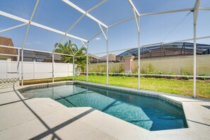 Une piscine dotée d’un espace couvert, entourée d’une clôture blanche et d’une pelouse verdoyante.