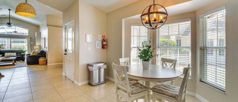 A spacious kitchen with a dining area, large windows, and a ceiling fan.