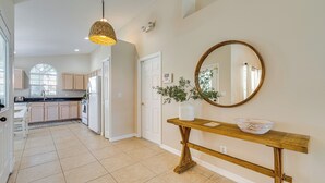 A spacious kitchen with white cabinets, a large window, and a wooden console table with a bowl and vase.