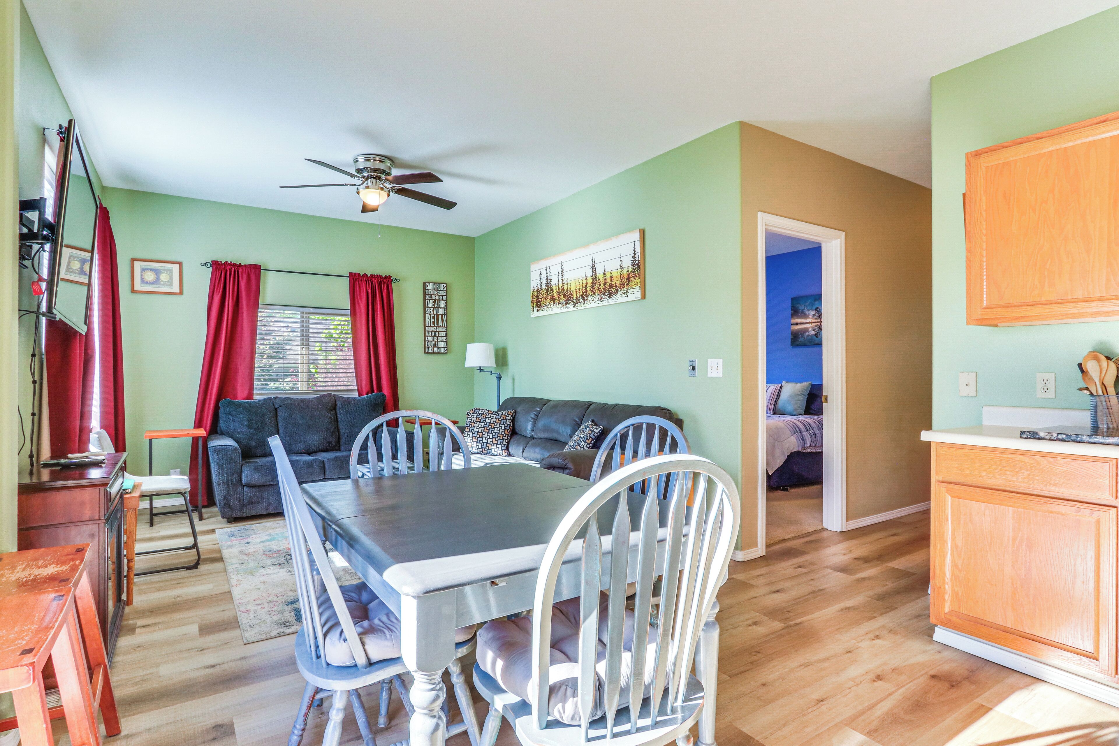 A dining area with a table and chairs, a sofa, and a ceiling fan.