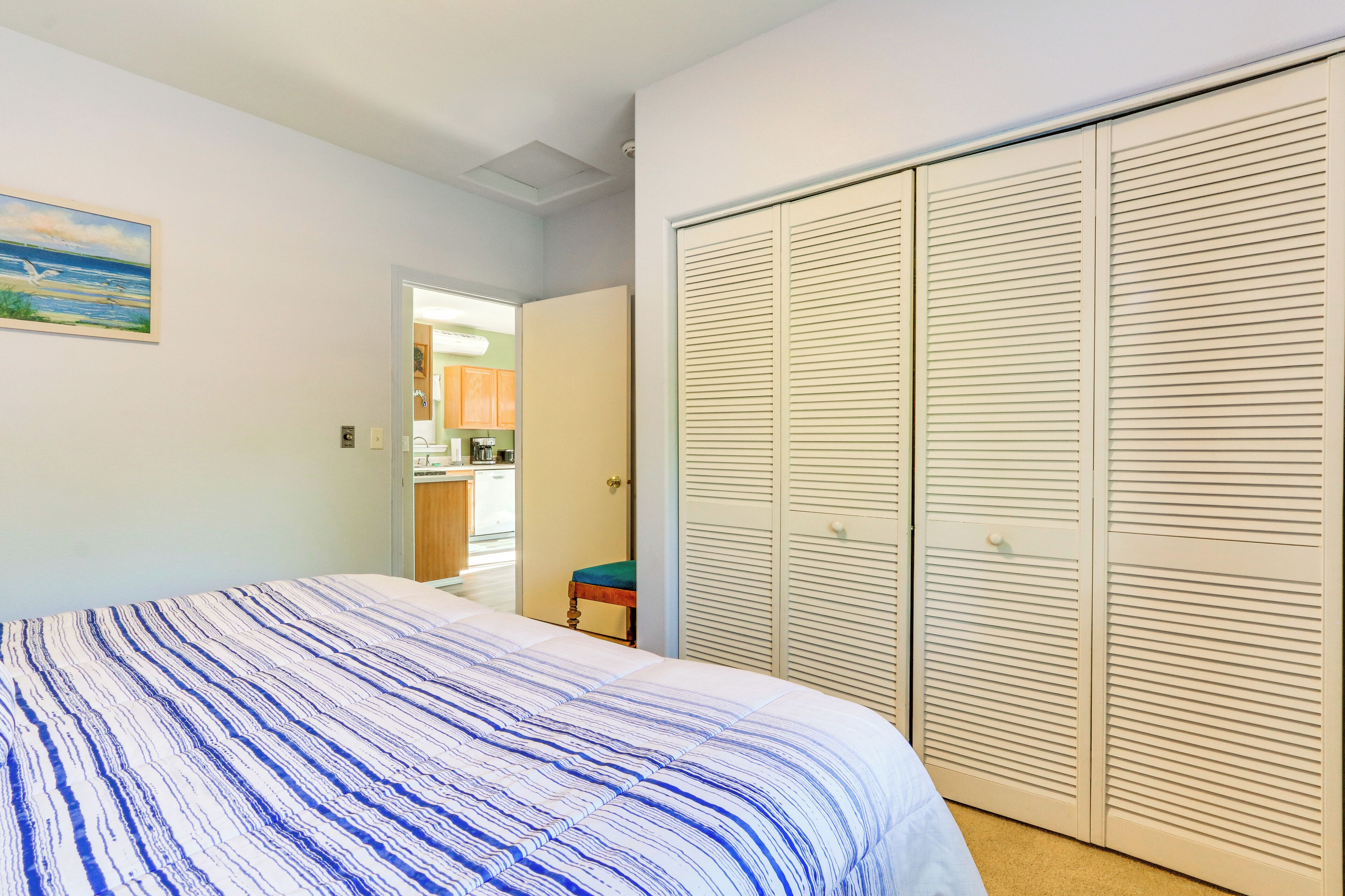 Un dormitorio con cama, armario y vistas a una cocina.