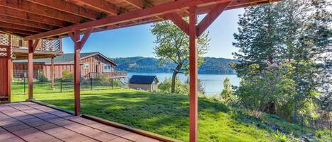 A covered patio with a view of a lake and mountains.