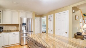 A kitchen with white cabinets, stainless steel appliances, and a marble countertop. - Beach & Lake Access: Group Getaway in Mashpee! (Mashpee)