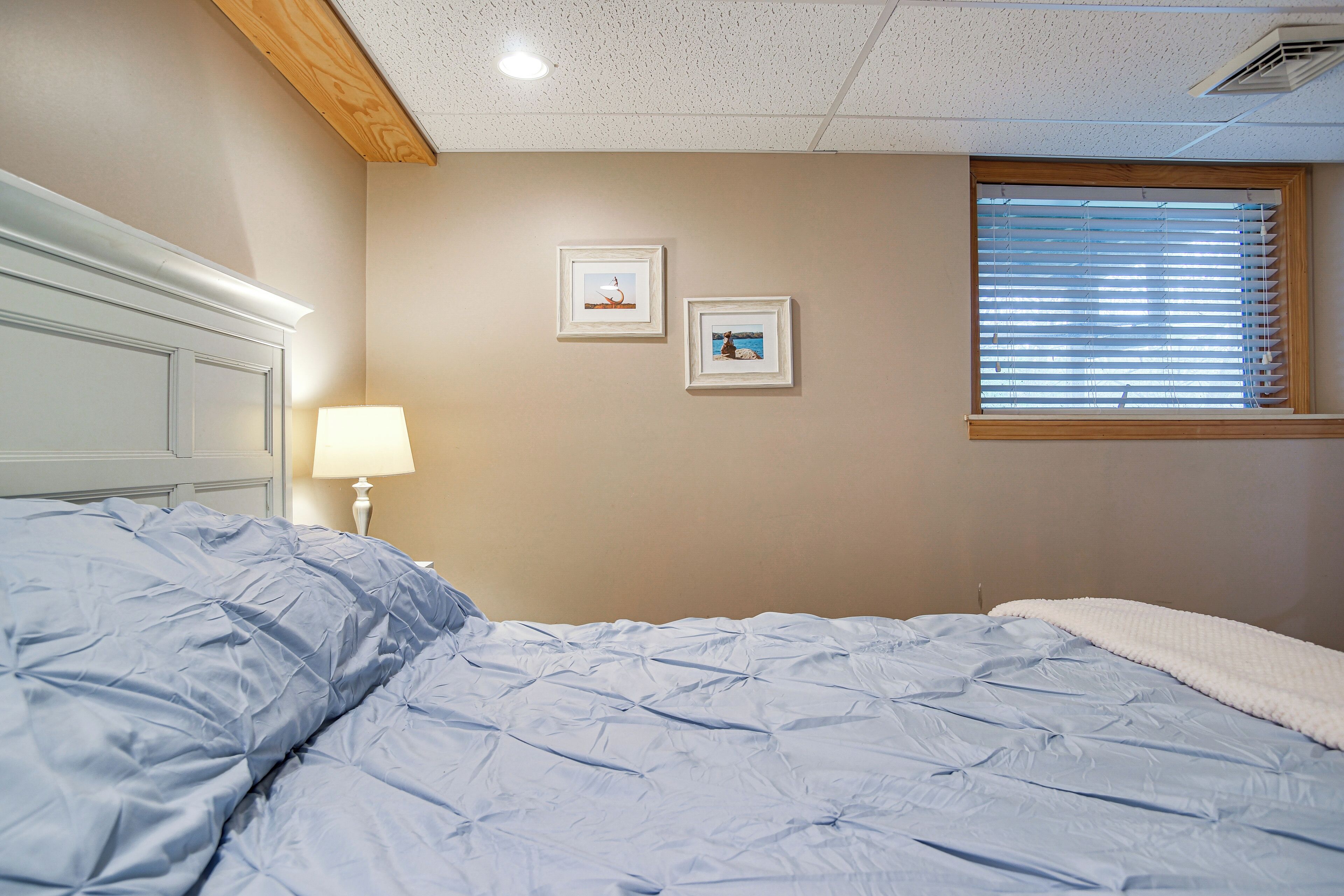 A bedroom with a bed, a nightstand, a lamp, and two framed pictures on the wall.
