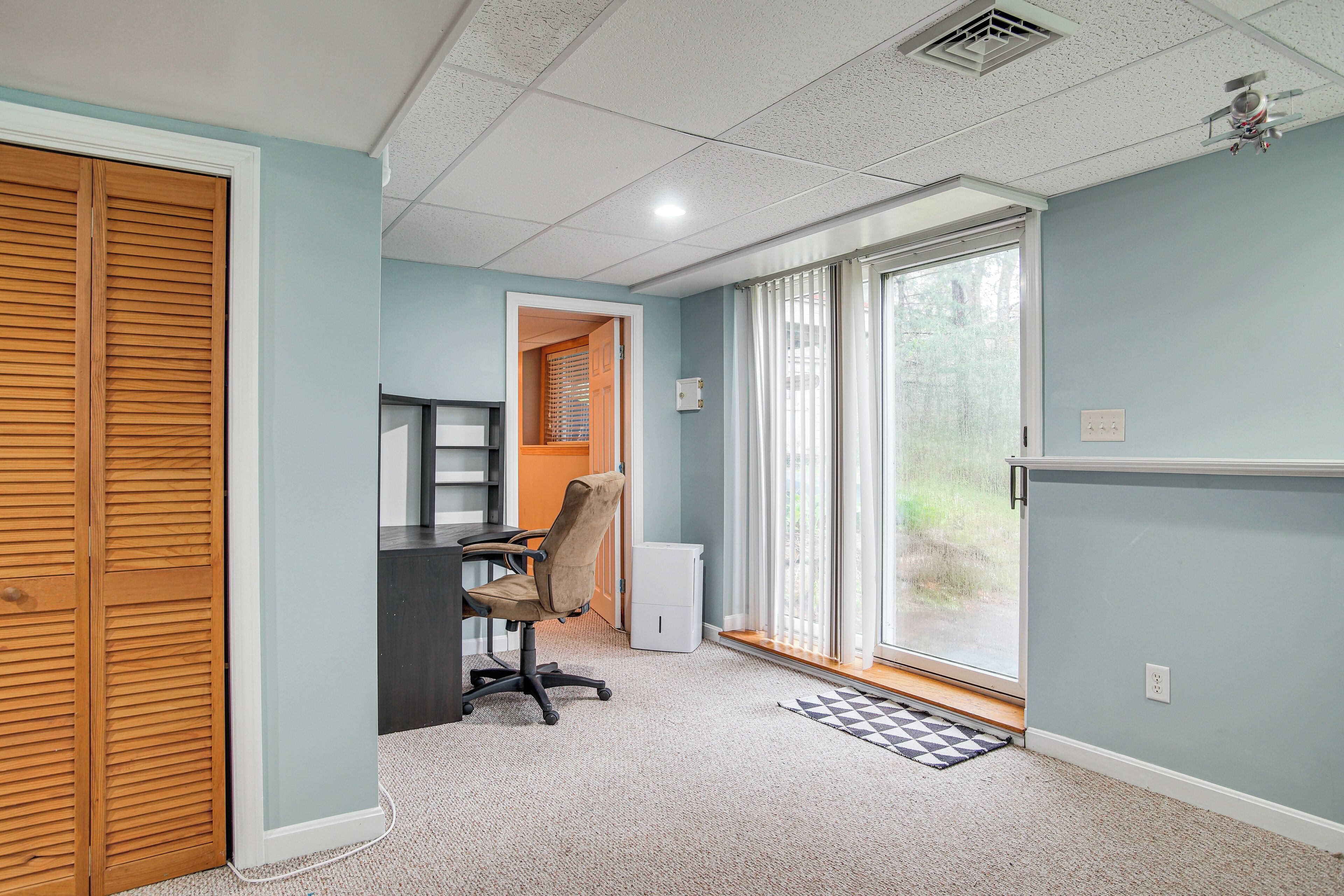 A room with a desk, chair, and a sliding door closet.