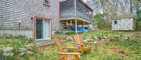 Una casa con un porche cubierto y dos sillas Adirondack.