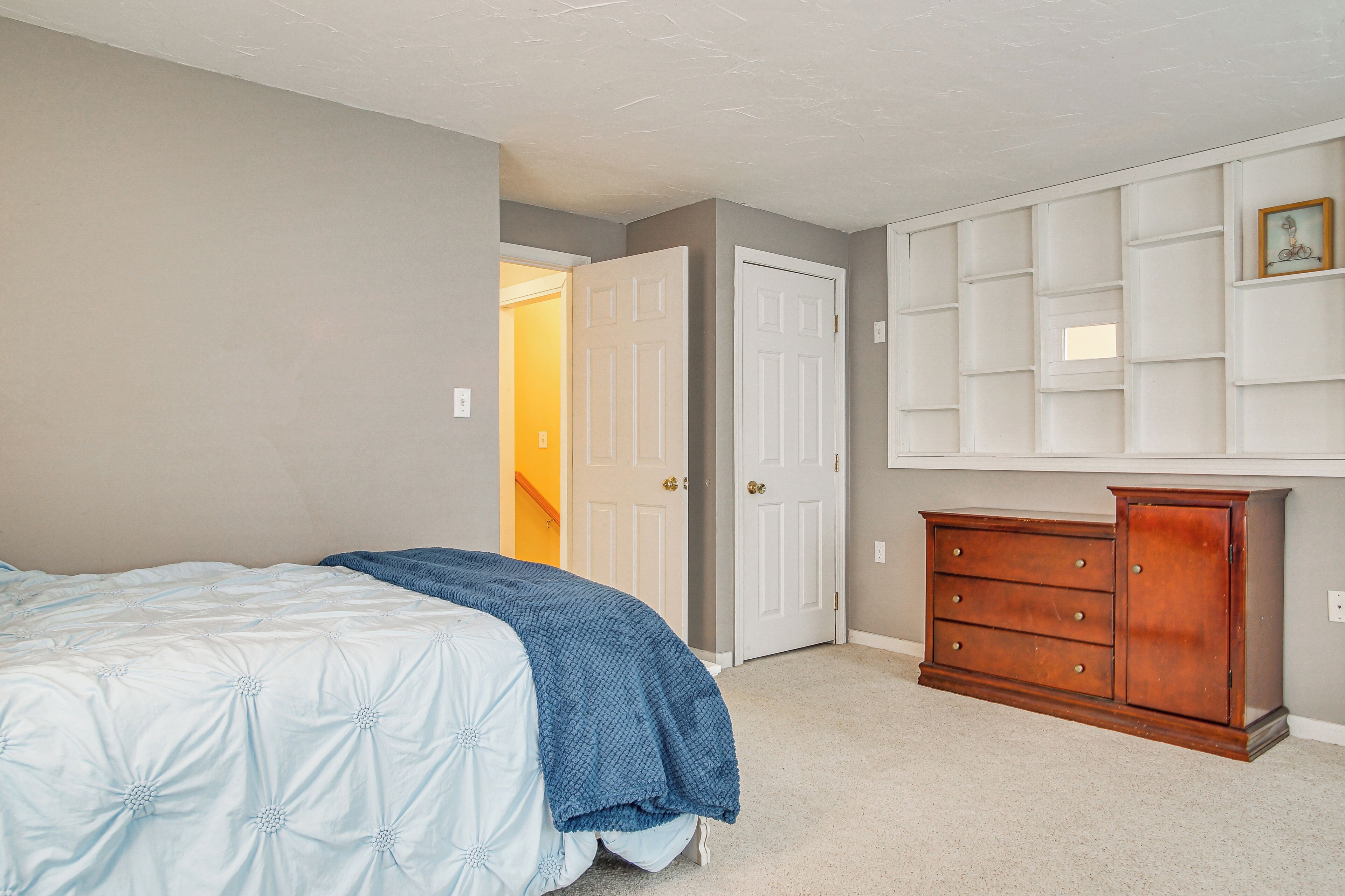 Un dormitorio con una cama, un aparador y una puerta que da a otra habitación.