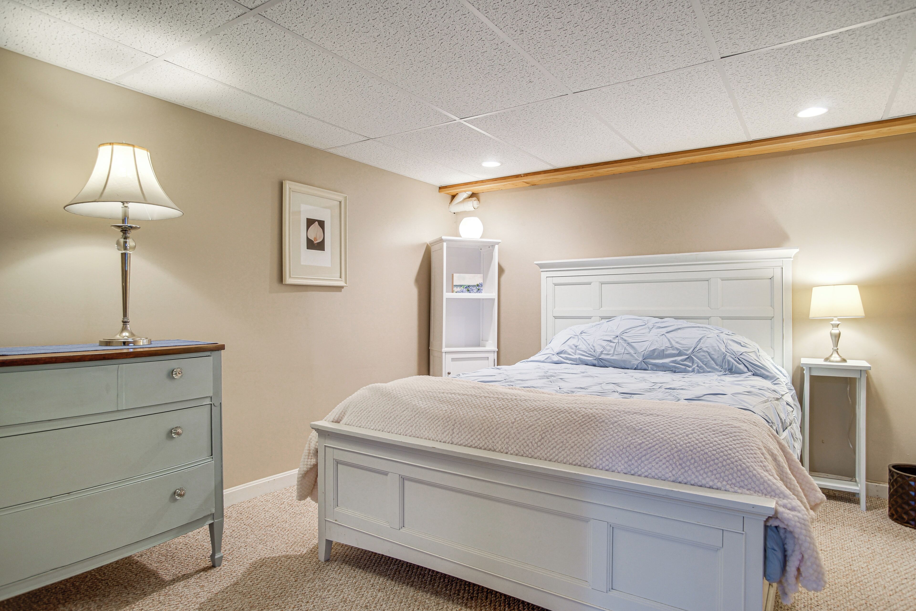 A bedroom with a bed, dresser, bedside tables, and a ceiling light fixture.