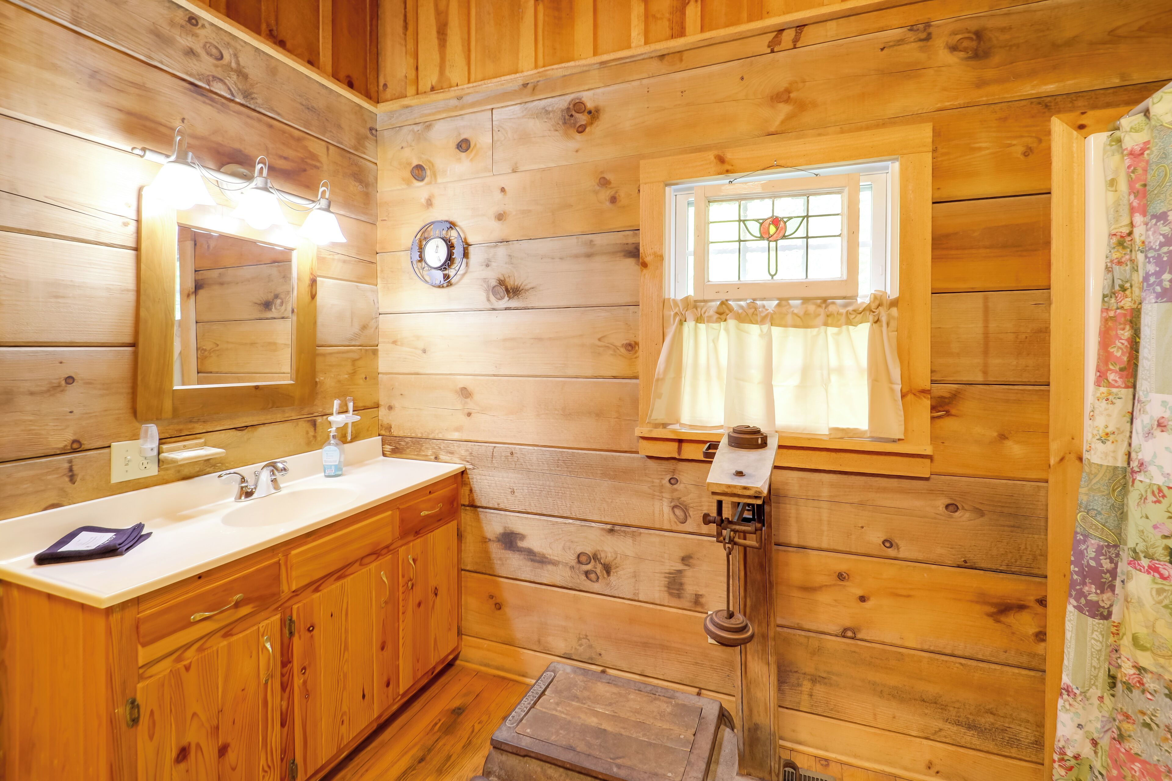 Une salle de bain rustique, aménagée dans une cabane en bois, avec un lavabo, un miroir et une fenêtre.