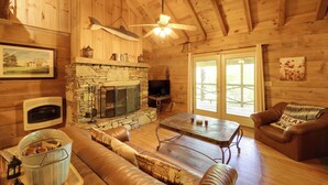 A cozy cabin interior with a stone fireplace, leather furniture, and a television. - Winter Hiking + Hot Tub Soaks! Marion Mtn Cabin (Marion)