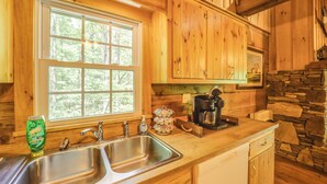 A wooden cabin kitchen with a large window, a sink, a coffee maker, and a stone wall. - Winter Hiking + Hot Tub Soaks! Marion Mtn Cabin (Marion)