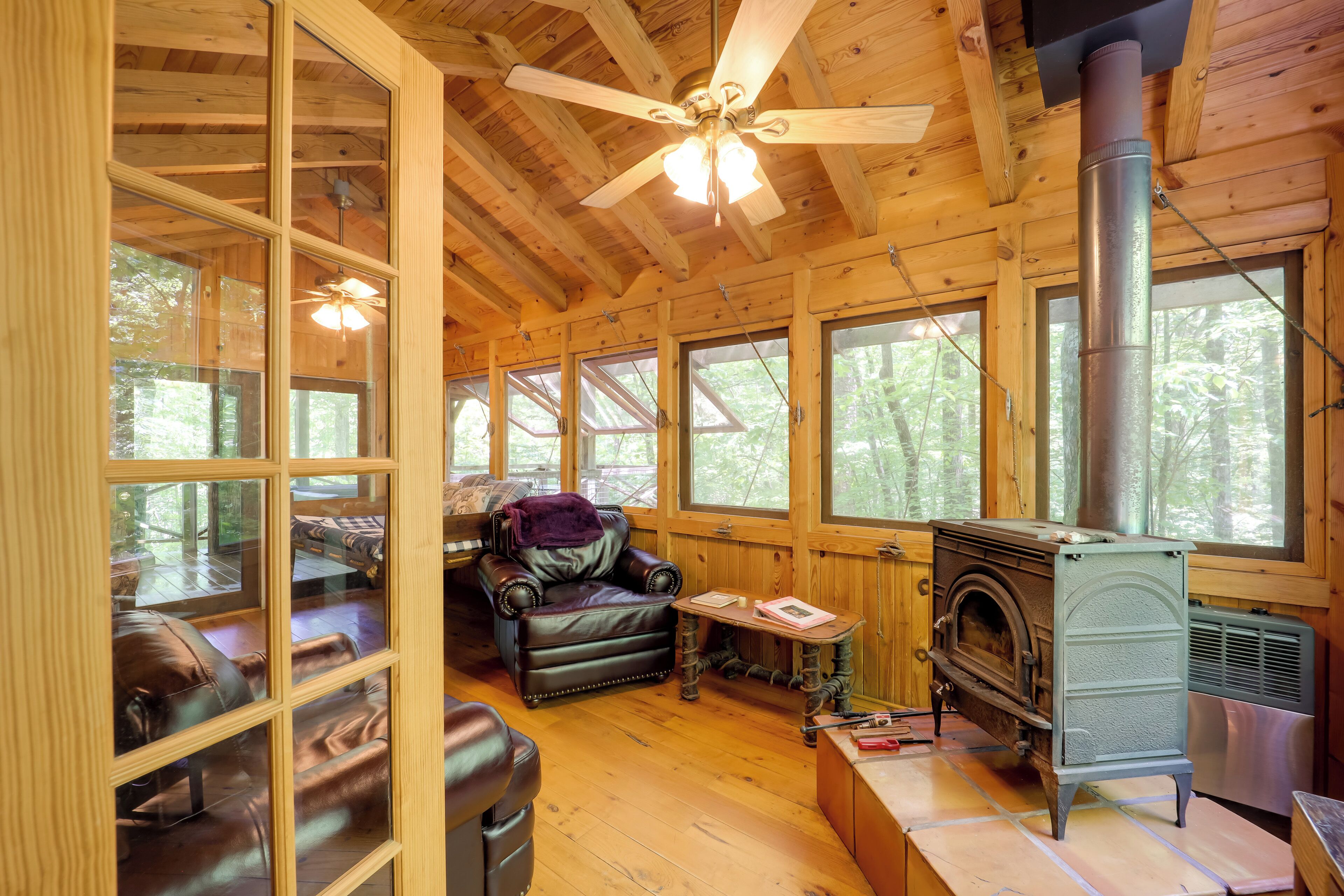 Ein gemütliches Blockhaus-Interieur mit Kamin, Ledermöbeln und großen Fenstern.