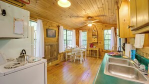 L’intérieur d’un chalet en bois comprend une cuisine, un coin repas et un ventilateur de plafond.