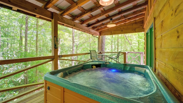 A wooden cabin with a hot tub, wooden deck, and a view of the forest. - Hot Tub & Trail Access: 92-acre Retreat in Marion! (Marion)