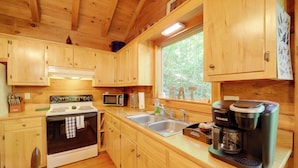 A wooden cabin kitchen with a stove, microwave, sink, and Keurig coffee maker. - Hot Tub & Trail Access: 92-acre Retreat in Marion! (Marion)