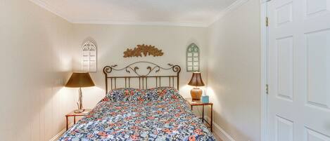 A bedroom with a floral bedspread, two bedside lamps, and a decorative wall piece.