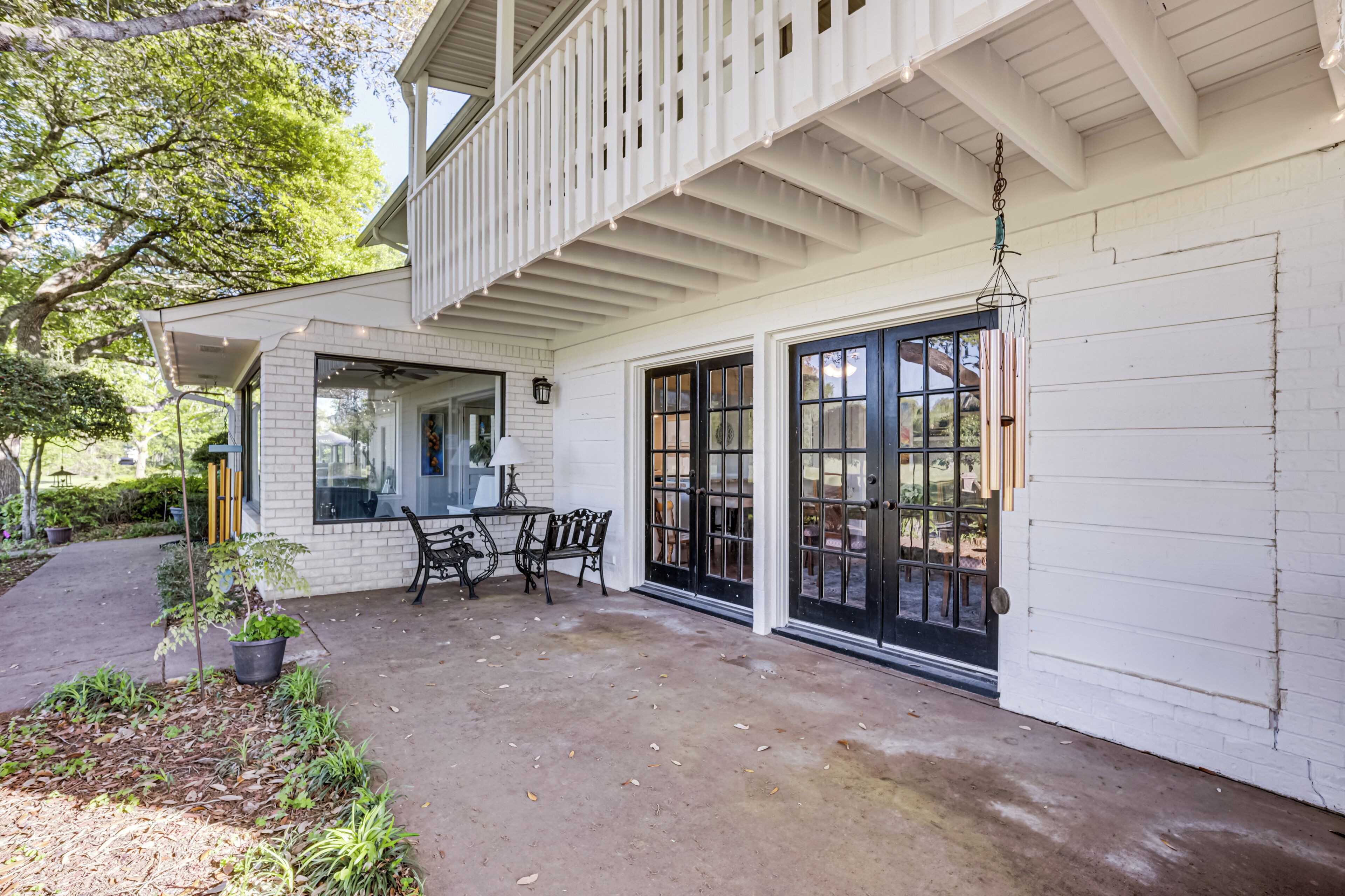 A white building with a covered porch, black-framed windows, and a hanging light fixture.