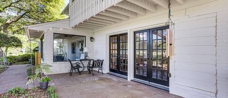 A white building with a covered porch, black-framed windows, and a hanging light fixture.