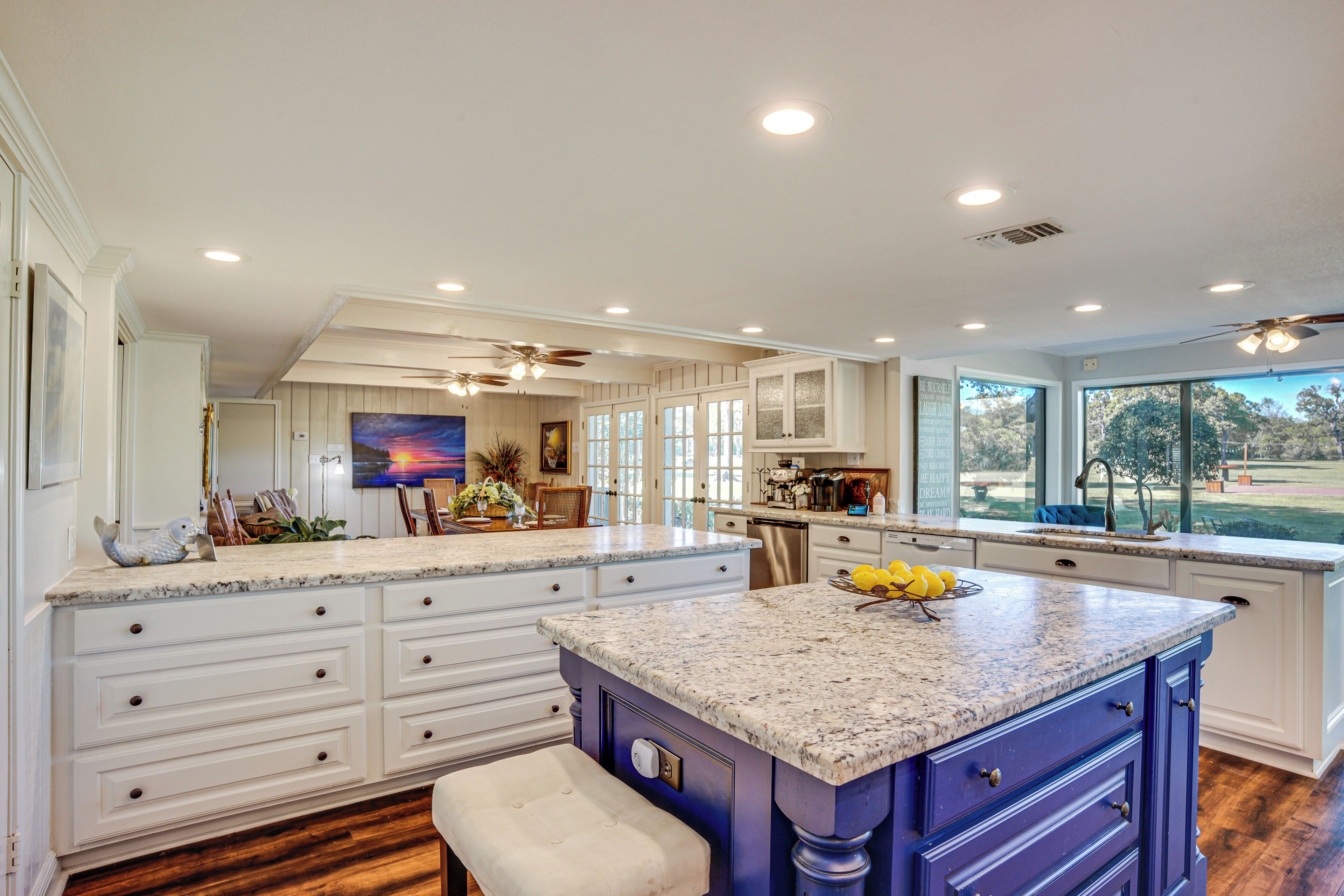 A spacious kitchen with a large island, white cabinetry, and a view of the outdoors.