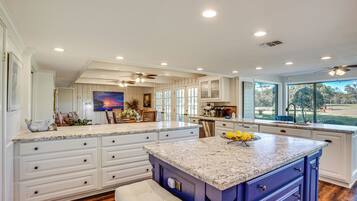 A spacious kitchen with a large island, white cabinetry, and a view of the outdoors.