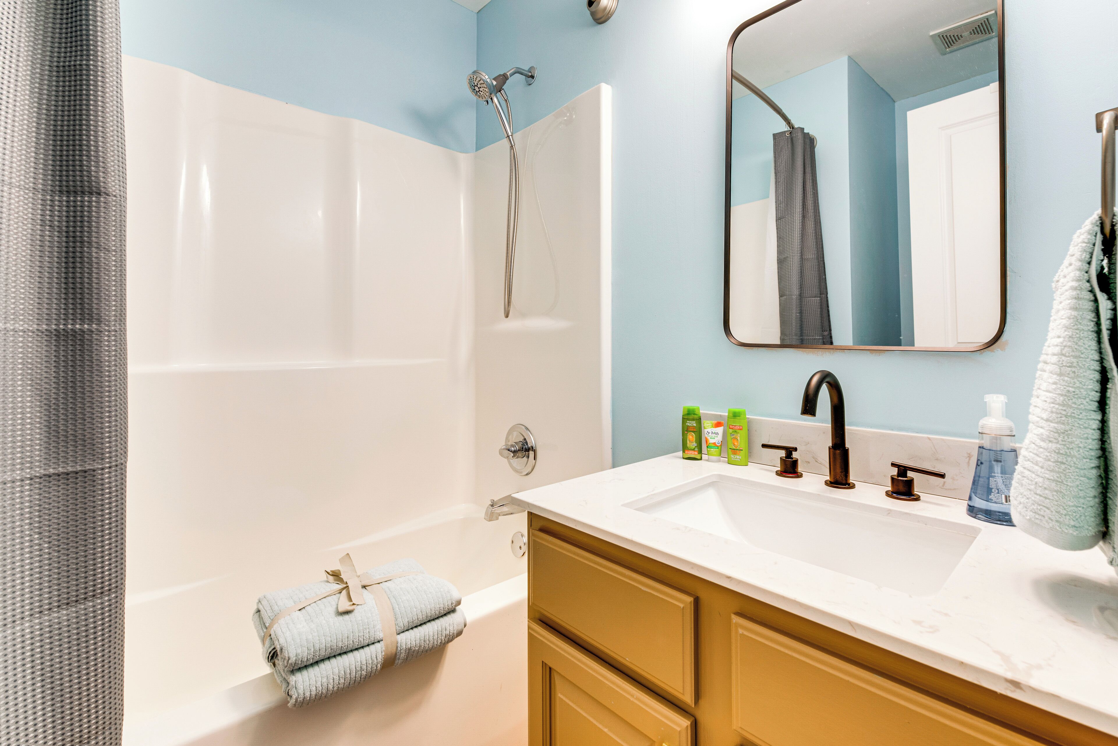 Une salle de bain avec une baignoire, un lavabo, un miroir et un porte-serviettes.