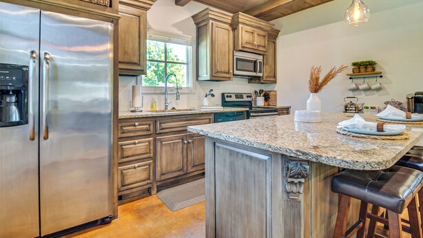 A modern kitchen with wooden cabinets, stainless steel appliances, and a granite countertop.