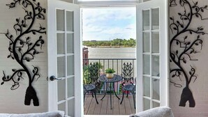 Een open deur, met uitzicht op een rivier en een balkon met tuinmeubilair.