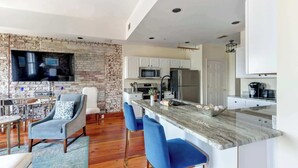 A modern kitchen with white cabinets, a marble countertop, and a built-in oven. - The Riverfront Loft, Charming | River Views (Savannah)