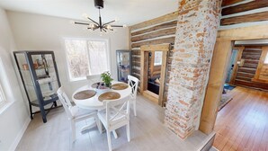 A dining area with a round table, white chairs, and a glass cabinet with decorative items. - Rustic & Refined - Gunnison (Gunnison)