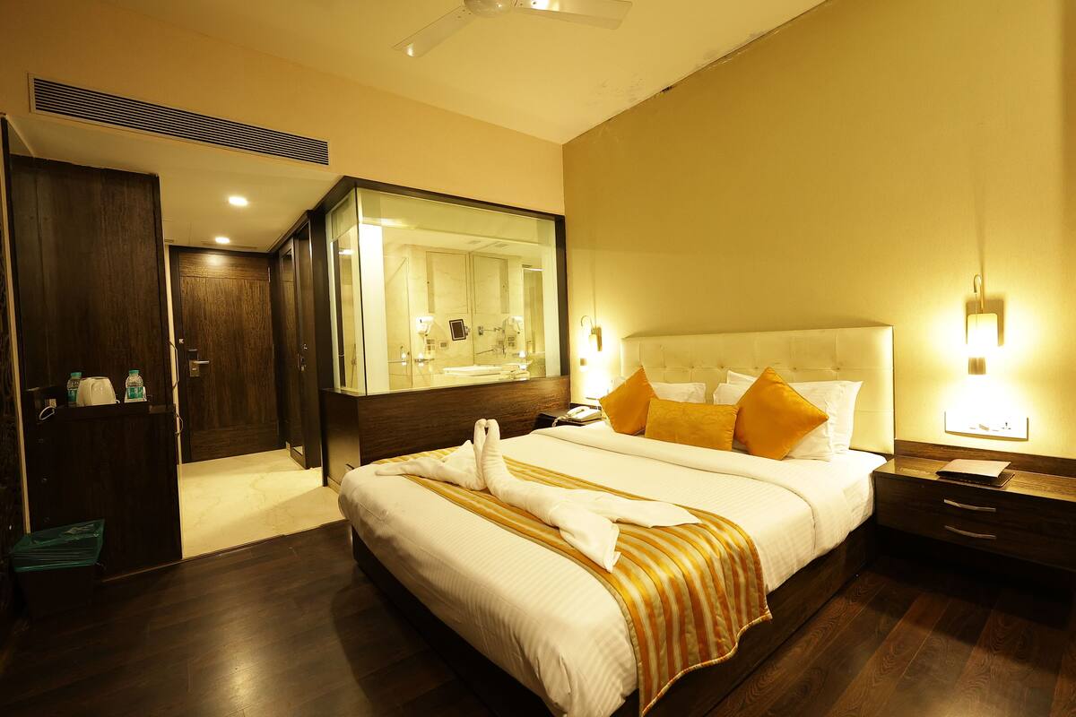 Habitación de hotel con una cama grande, una mesita de noche con lámpara, un tocador y un armario.