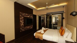 A hotel room with a large bed, a ceiling fan, a TV, and a mirror. - Kailash Parbat (Mawal)