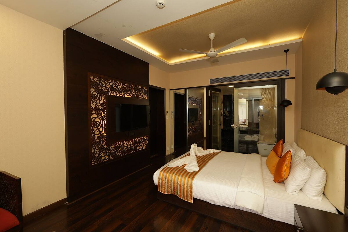 Habitación de hotel con una cama grande, ventilador de techo, televisor y espejo.