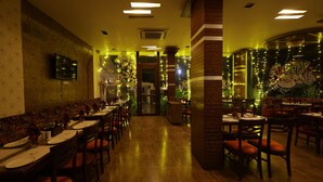 A restaurant with wooden flooring, multiple dining tables, and chairs. - Kailash Parbat (Mawal)