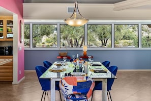 A dining area with a table set for four, large windows, and a view of trees.