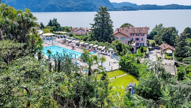 Ein Resort mit Schwimmbad, Liegestühlen und Blick auf einen See und Berge.