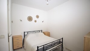 Une chambre à coucher comprenant un lit, une commode en bois, une table de chevet et des éléments de décoration murale.