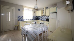 Une cuisine équipée d’une table à manger, de chaises, d’un petit tabouret, d’un réfrigérateur et d’un évier.