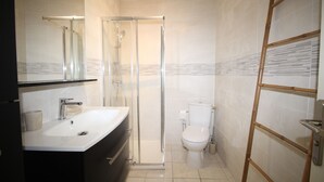 Une salle de bain moderne avec une douche à parois de verre, un lavabo blanc et des toilettes.