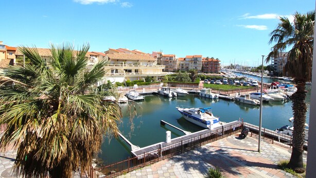 A marina with boats docked, surrounded by residential buildings and palm trees. - Studio for 4 with marina view (Canet-en-Roussillon)