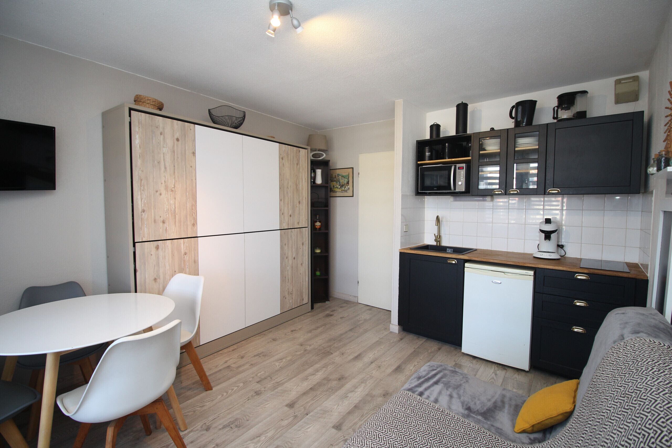 Una cocina compacta con comedor, un sofá y un televisor.