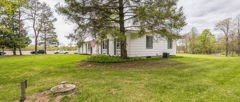 A single-story mobile home with a well-maintained lawn and a large tree in front.