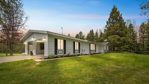 A modern two-story house with a well-maintained lawn and a driveway leading to the entrance. - Serene Riverside Retreat 3 Bedroom Home by RedAwning (Little Suamico)