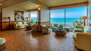 A spacious lobby with a large window offering a view of the ocean, furnished with sofas and armchairs, and a tiled floor. - Royal Kahana 1211 2 Bedroom Condo (Lahaina)