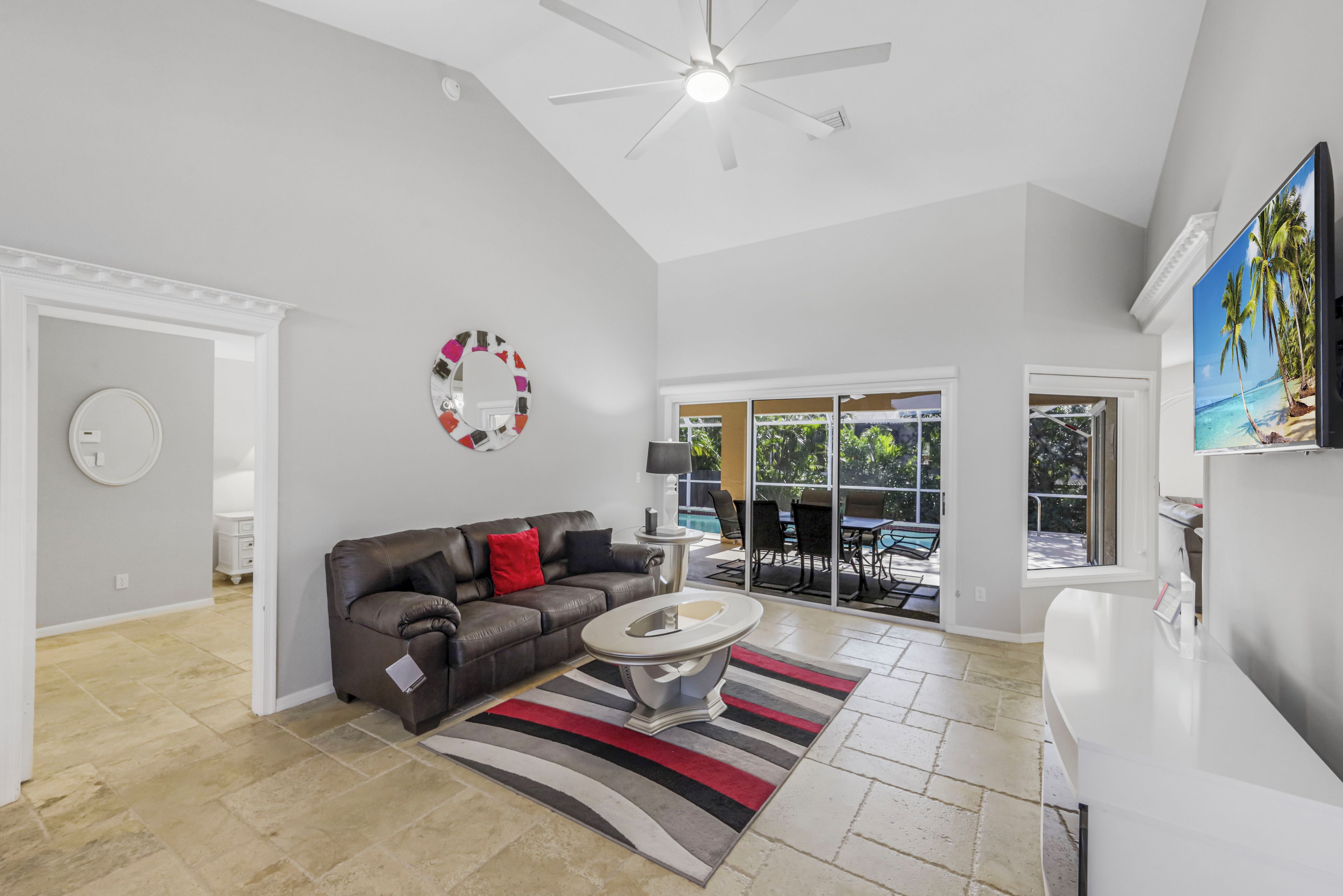 A spacious living room with a leather sofa, a coffee table, and a large window offering a view of the outdoors.