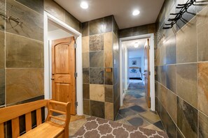 Stylish hallway with a wooden bench and stone floor, leading to a cozy room with a comfortable bed.
