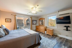 Relax in a spacious bedroom with a large bed, ceiling fan, and entertainment options.